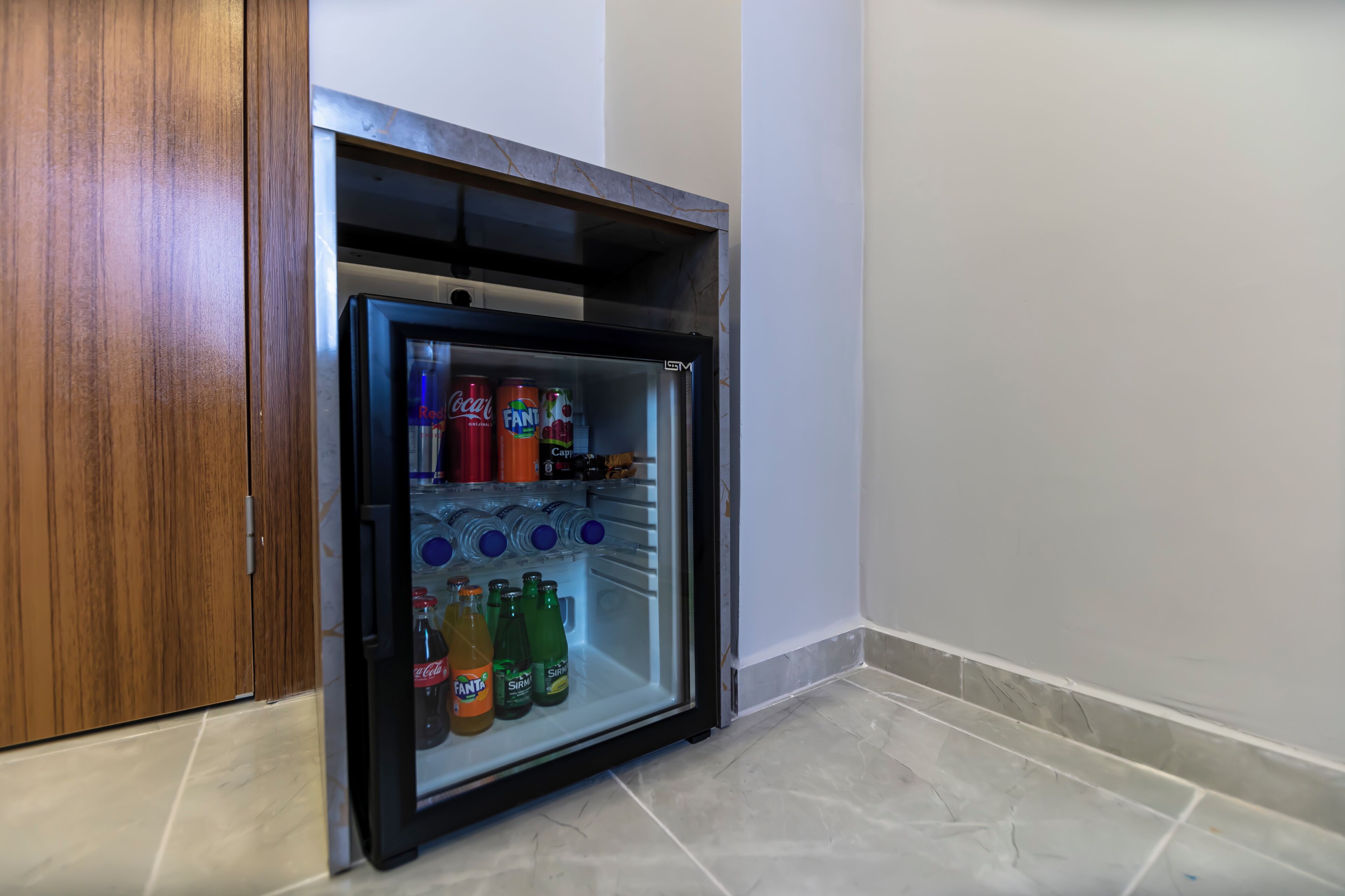 A small refrigerator with a wooden door, containing various beverages and a bottle of Coca-Cola.
