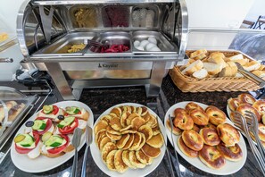 A buffet with various food items including bread, eggs, and a plate of pancakes with toppings. - Gul Otel (Istanbul)