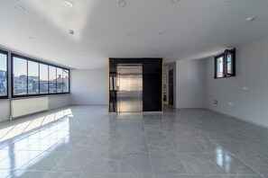 A spacious, modern room with large windows, a tiled floor, and a view of the city. - Gul Otel (Istanbul)