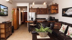 A modern kitchen with wooden cabinets, a refrigerator, and a dining area. - Lpb-2d (Jacó)