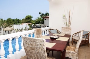 Enjoy meals in this dining area with a wooden table and wicker chairs, surrounded by a view of the surrounding landscape.