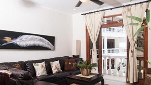 A living room with a dark leather sofa, a coffee table, and a large feather artwork on the wall. - Lpb-2d (Jacó)