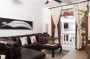 Relax in style with a comfortable sofa, a statement artwork, and a balcony leading to an outdoor space.
