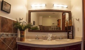 A bathroom with two sinks, a large mirror, and a potted plant.