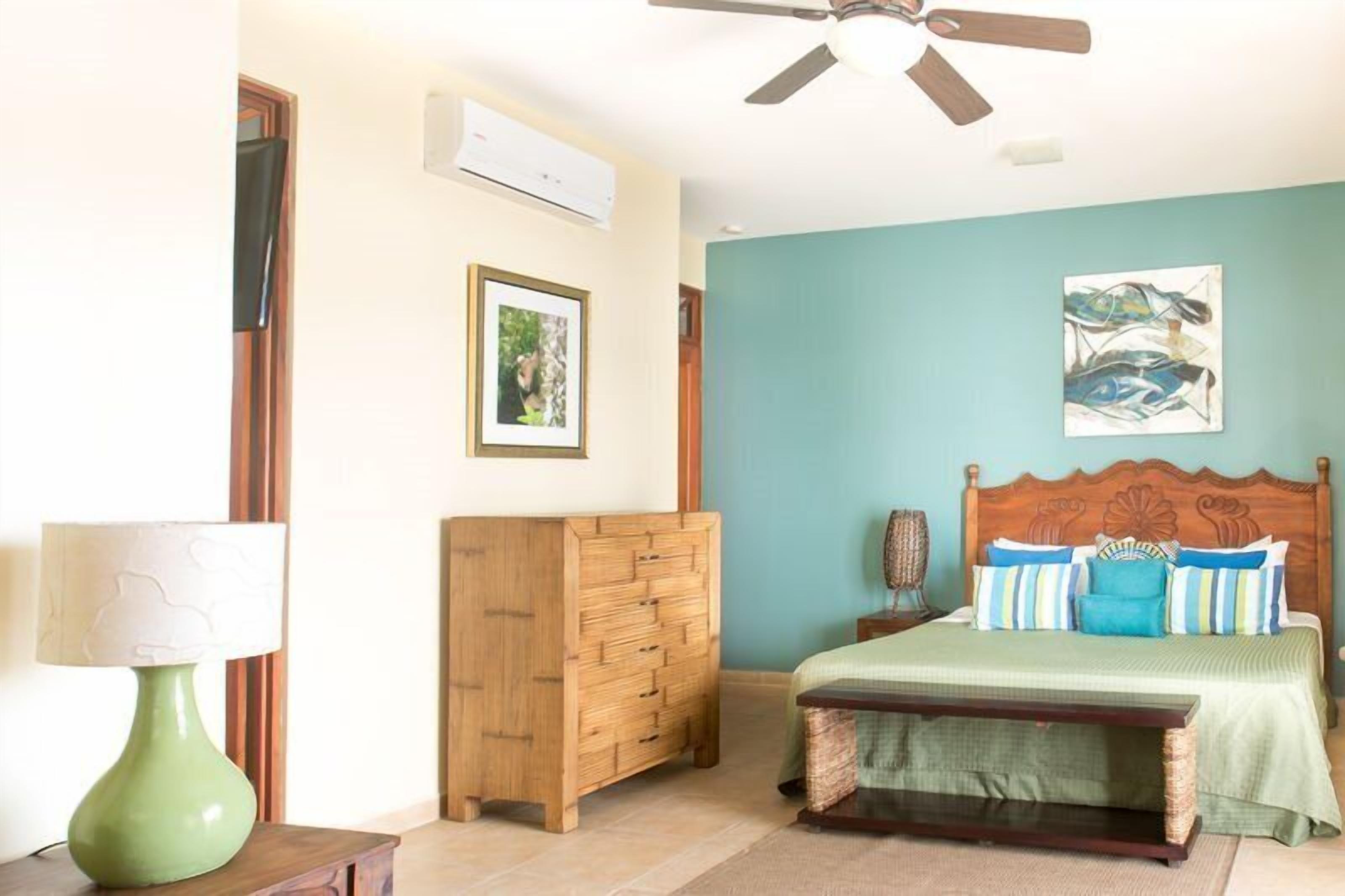 Une chambre à coucher avec un lit, une commode en bois et un ventilateur de plafond.