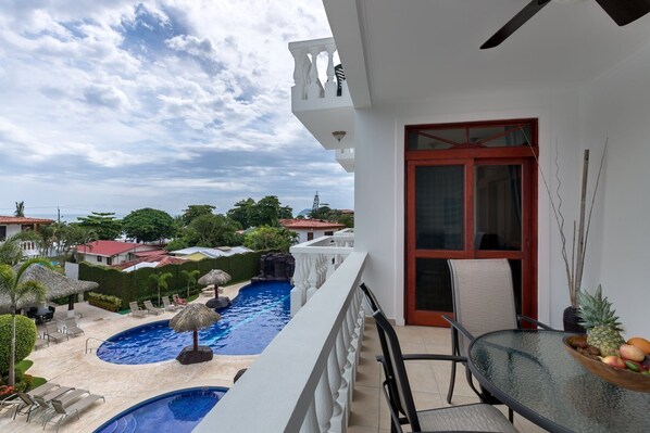 A balcony with a view of a swimming pool and surrounding greenery.