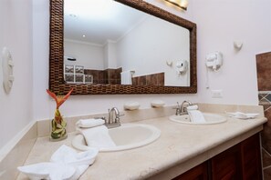 A bathroom with two sinks, a large mirror, and a vase with flowers.