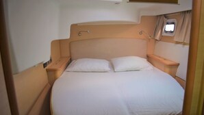 A single bed with a headboard, two pillows, and a bedside table with a lamp. - Catamaran Lagoon by Veleros Colombia (Cartagena)