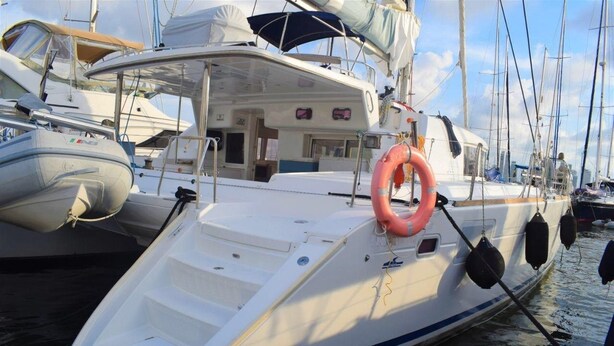 A white yacht docked at a marina with a lifebuoy attached to the side. - Catamaran Lagoon by Veleros Colombia (Cartagena)