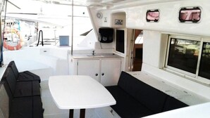 A compact galley with a sink, a small cabinet, and a seating area with a table and benches. - Catamaran Lagoon by Veleros Colombia (Cartagena)