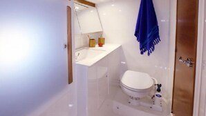 A compact bathroom with a white toilet, a sink, and a mirror. - 45 Sailboat Veleros Colombia (Cartagena)