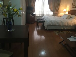 A hotel room with a bed, a TV, a desk, and a vase of flowers. - Apart Hotel Dos Providencia (Santiago)