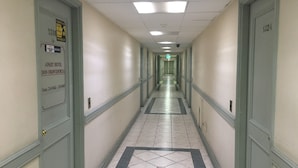 A hotel hallway with doors on both sides, a tiled floor, and a ceiling with fluorescent lights. - Apart Hotel Dos Providencia (Santiago)