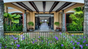 A covered walkway with stone pillars and potted plants, leading to a building entrance. - Terrific 2BR 1st Floor Unit is Sure to Please (Jacó)