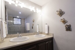A bathroom with two sinks, a large mirror, and decorative wall art.