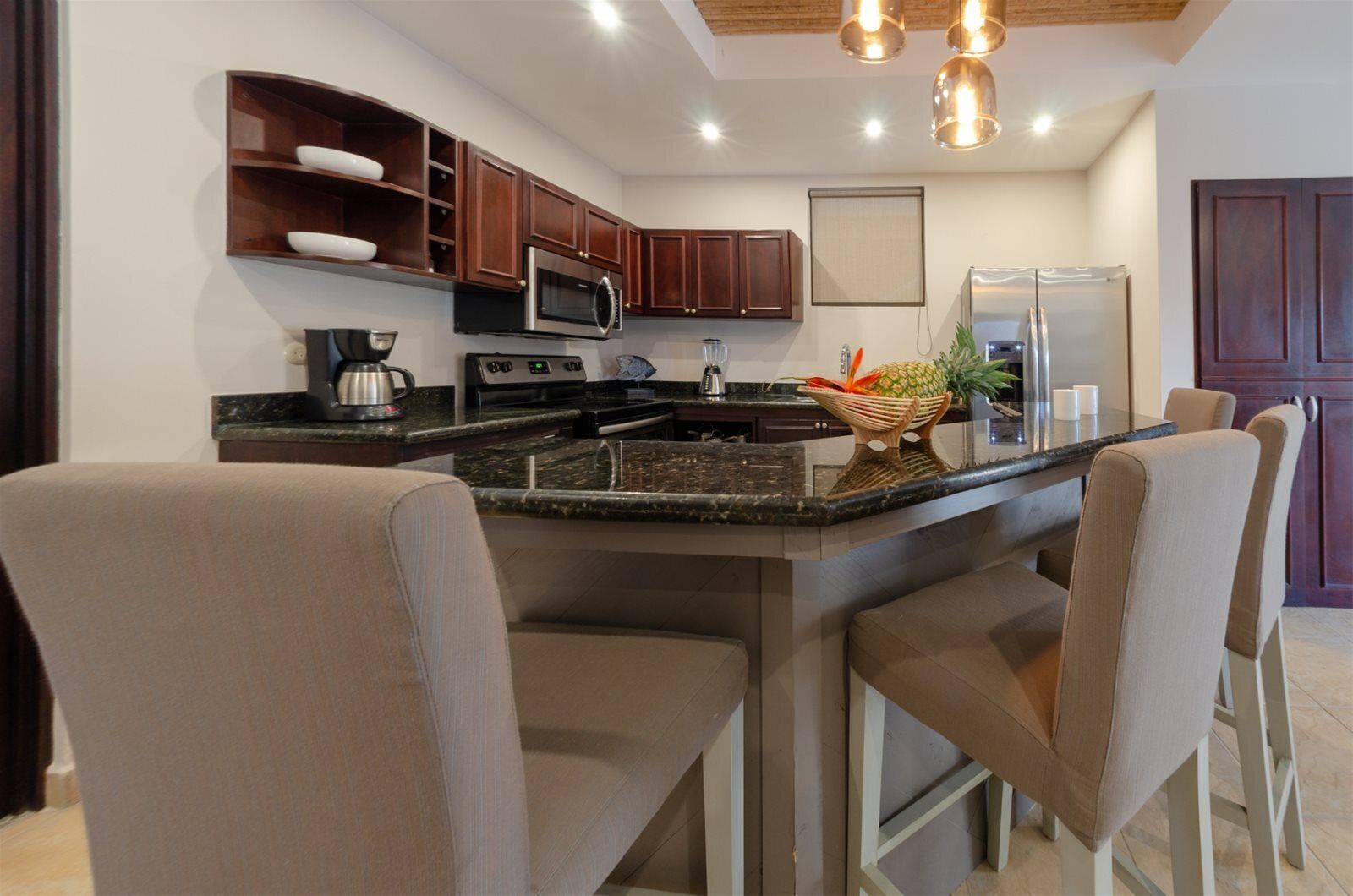 A modern kitchen with dark wood cabinets, stainless steel appliances, and a central island with bar stools.