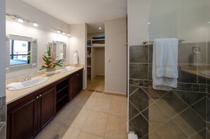 A modern bathroom with two sinks, a large mirror, and a glass shower enclosure.