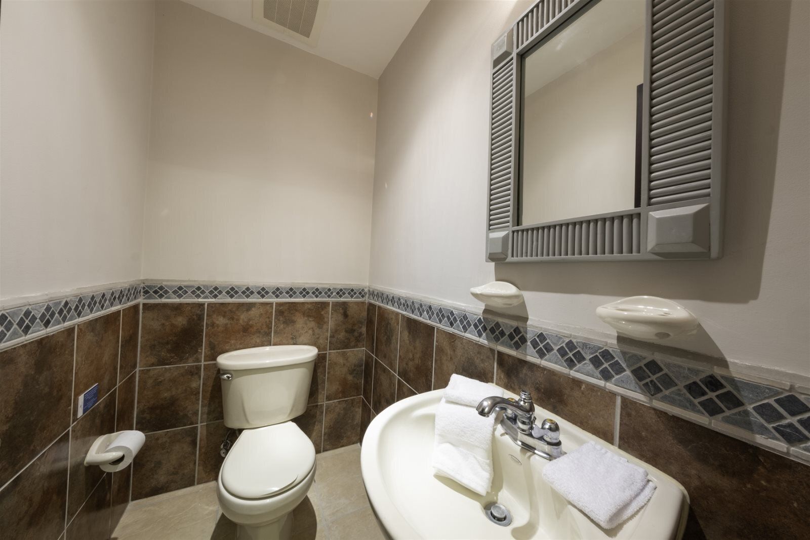 A bathroom with a toilet, sink, and mirror.