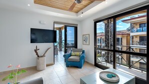 Ein geräumiges Wohnzimmer mit großem Fenster, Deckenventilator und flachbildschirm-Fernseher an der Wand.