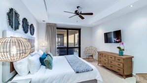Ein modernes Schlafzimmer mit Bett, Nachttisch, Kommode und Deckenventilator.