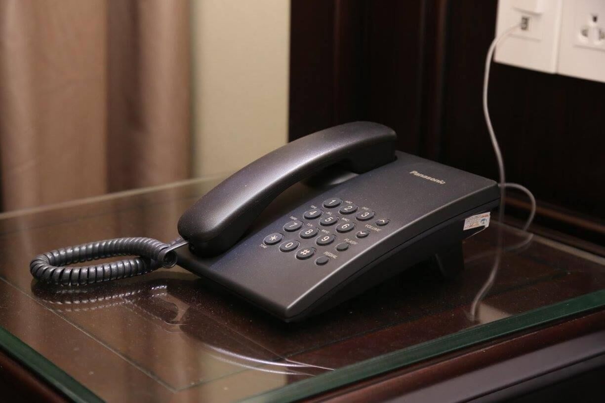 Un téléphone Panasonic posé sur un bureau dont le plateau est en verre.
