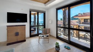 Ein geräumiges Zimmer mit großem Fenster, einem Flachbildfernseher, einem Korbschrank und einer Topfpflanze.