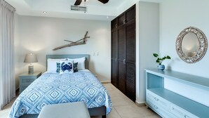 A bedroom with a bed, a ceiling fan, a nightstand, a dresser, a mirror, and a decorative branch on the wall. - 5th Flr Ocean View Penthouse With 2 Level Balcony (Jacó)