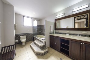 A bathroom with a toilet, bathtub, and a large mirror above the sink. - Perfect Oceanfront Retreat for Your Family (Jacó)
