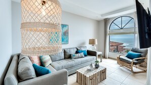 A modern living room with a grey sofa, a wicker coffee table, and a wicker armchair. - Perfect Oceanfront Retreat for Your Family (Jacó)