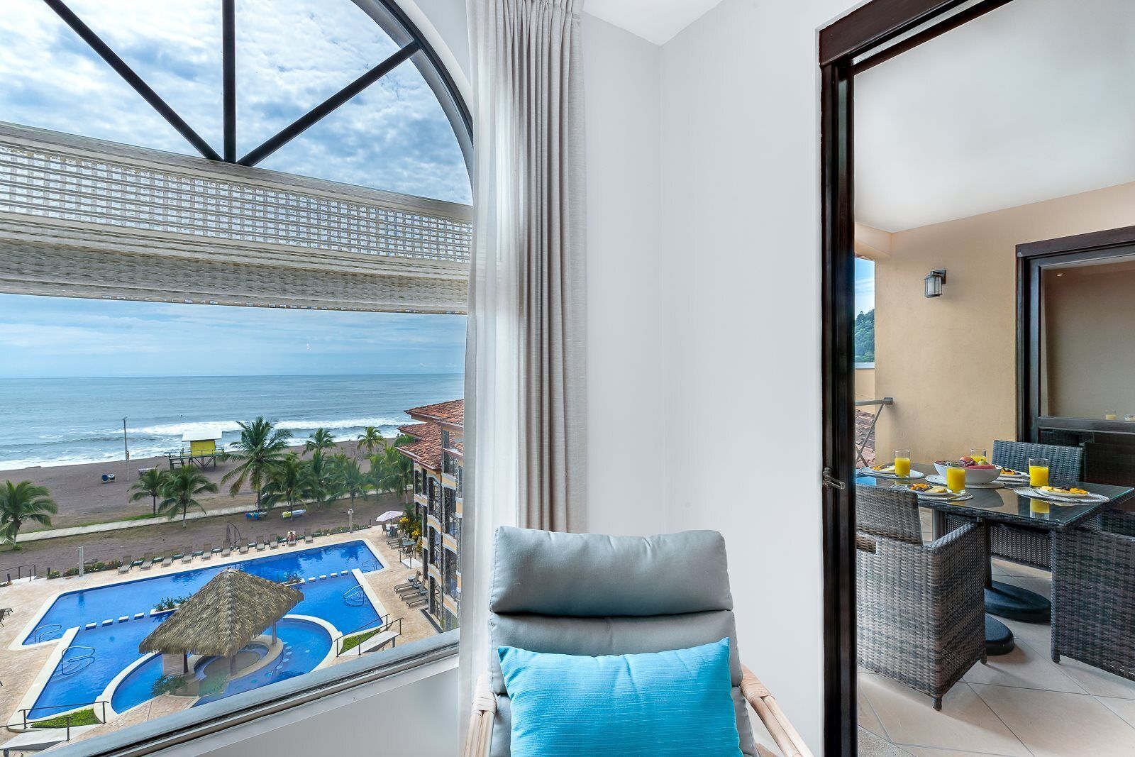 A balcony with a view of the ocean and a pool.