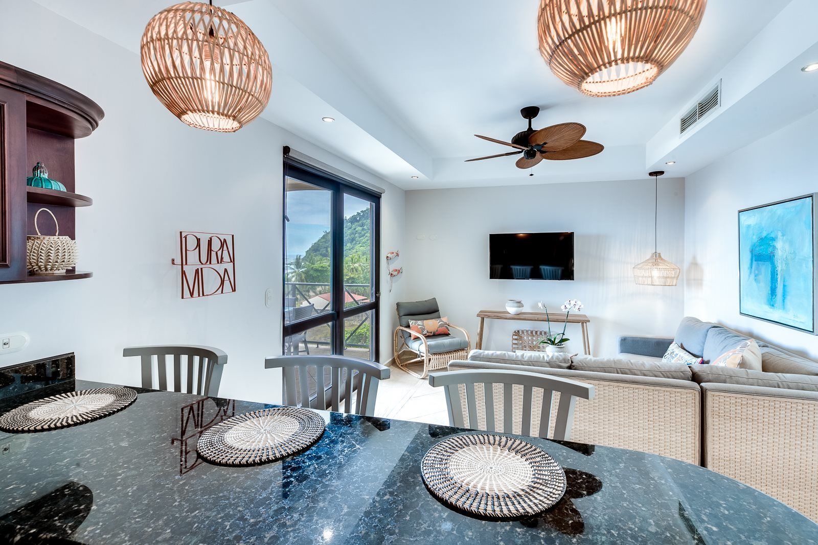 A modern dining area with a round table, chairs, and a ceiling fan.