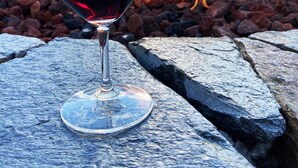 A glass of red wine on a stone surface with a fire in the background. - Stanford House (Manchester Center)
