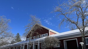 A two-story building with a red facade and white trim, featuring a garage and a covered porch area. - Stanford House (Manchester Center)