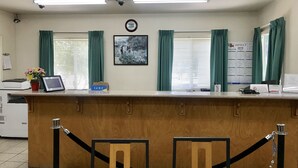 A reception desk with a clock, framed picture, and a sign indicating the room is for golf. - Sunrise Inn Turlock (Turlock)