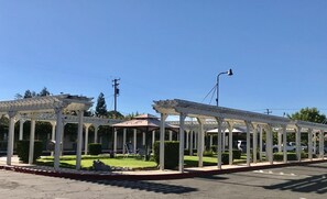 A covered outdoor seating area with white columns and a clear blue sky.