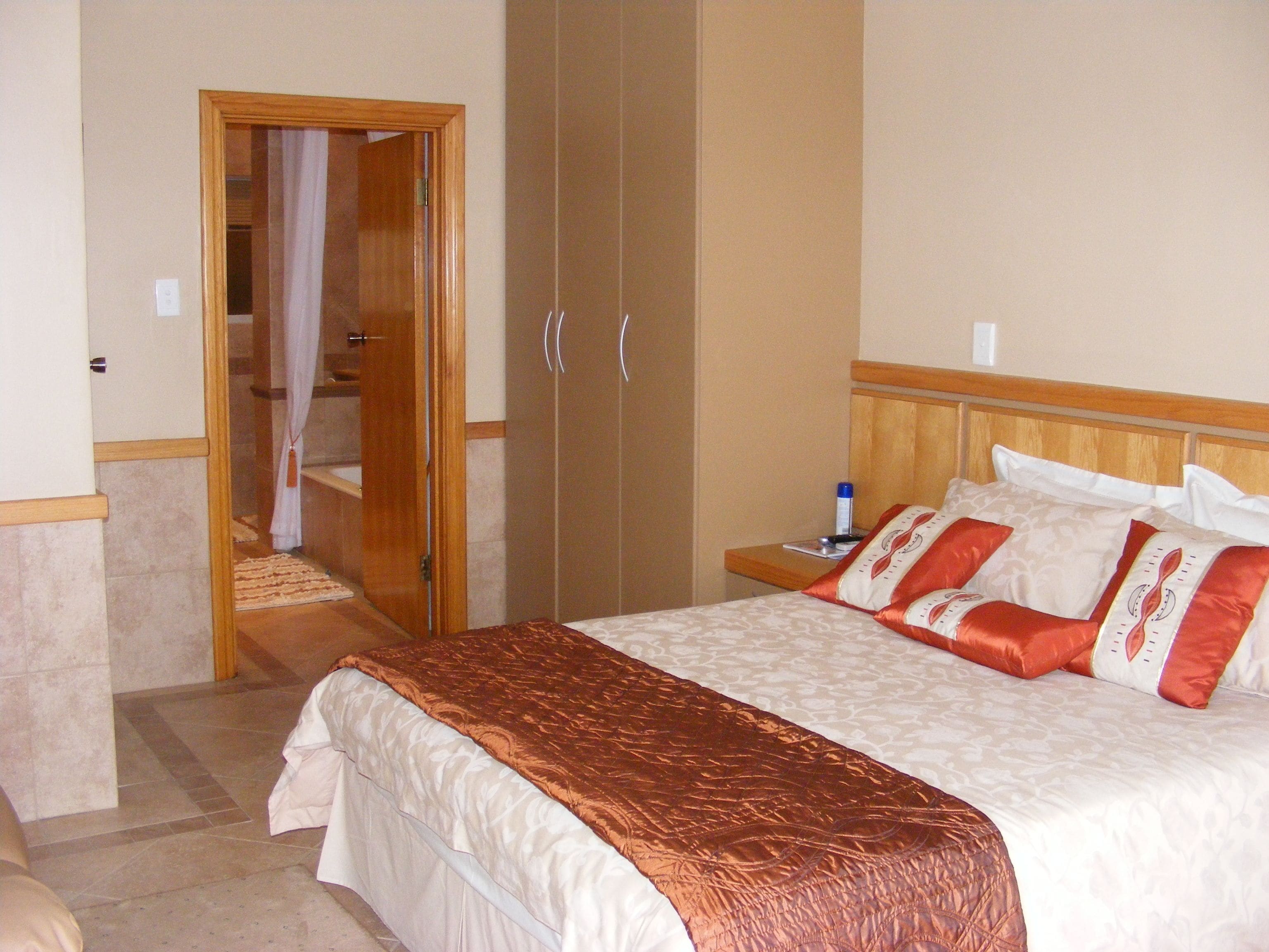 Una habitación de hotel con una cama, un armario de madera y un baño con cortina de ducha.
