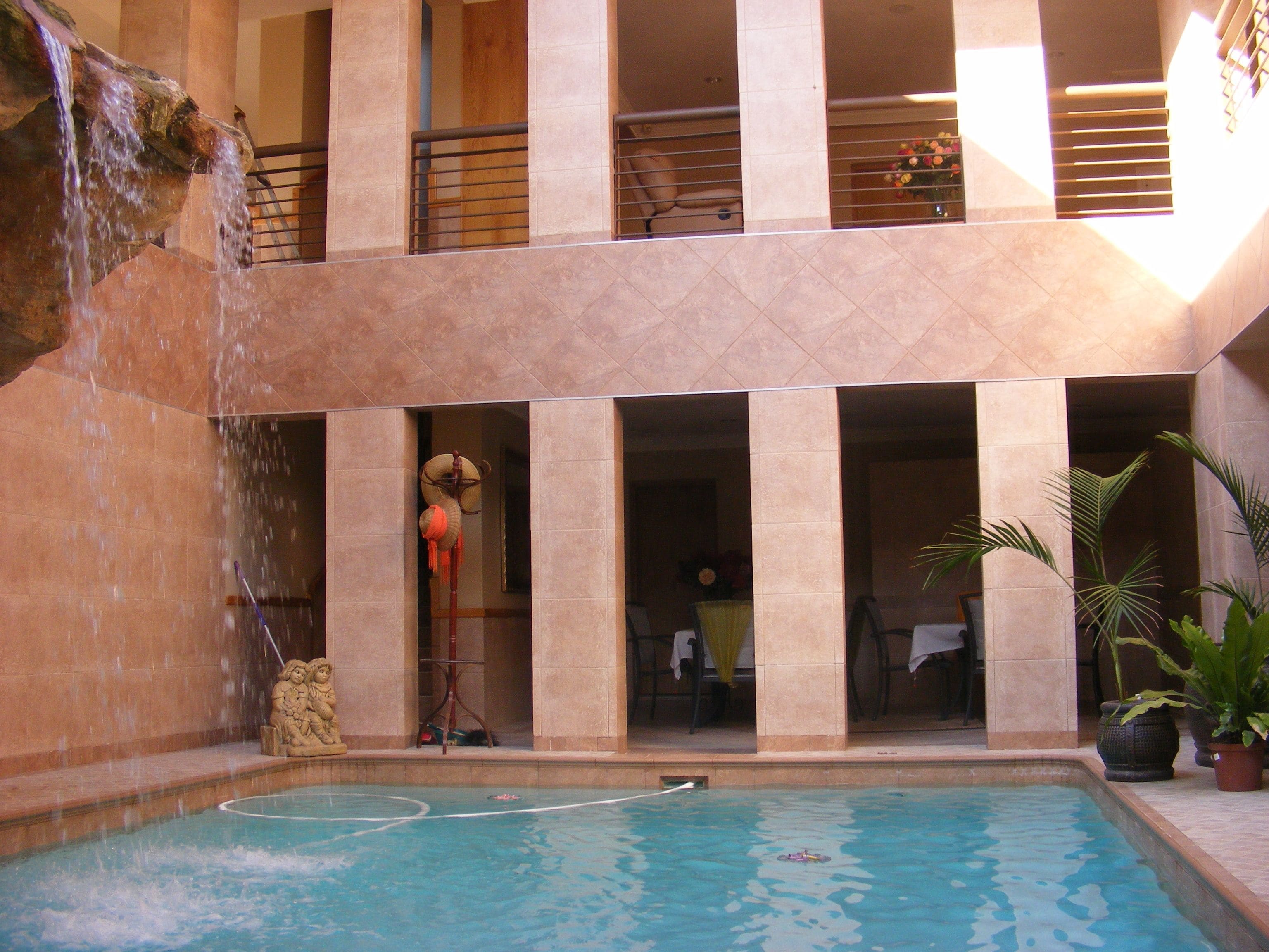 A pool area with a waterfall feature, a statue, and potted plants.