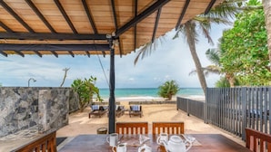 Un espacio de comedor al aire libre techado, con vistas a la playa y al océano.