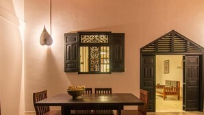 Un comedor con una mesa y sillas, un tapiz decorativo y una puerta que da a otra habitación.