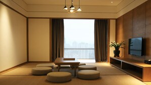 A modern living room with tatami mats, a low wooden table, and a TV on a wooden stand.