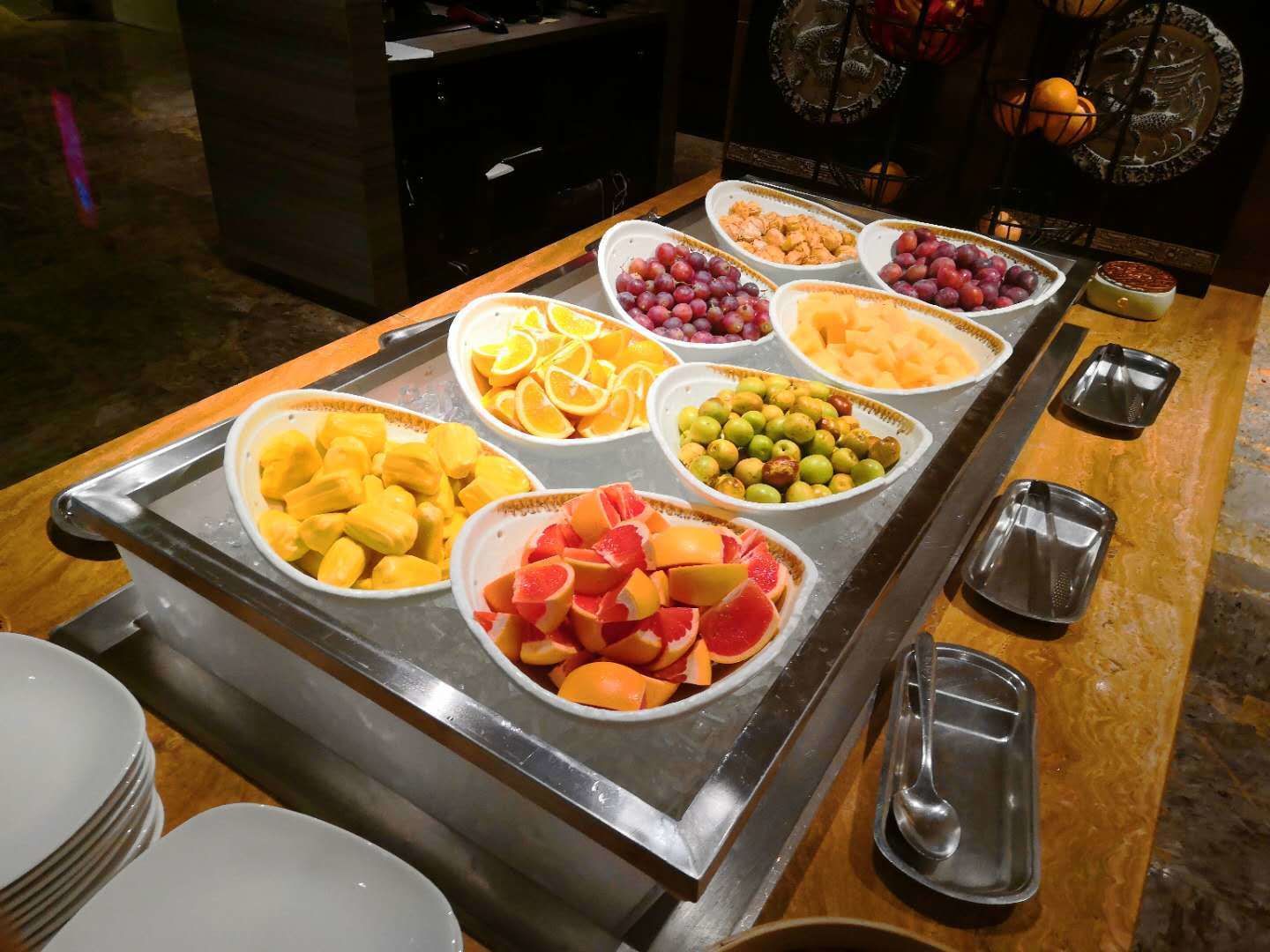 A buffet with various fruits and a dessert.