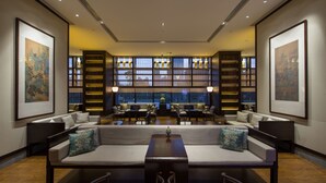 A spacious lobby with a central seating area, bookshelves, and framed artwork on the walls.