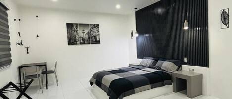 A modern bedroom with a large bed, a desk, and a chair.