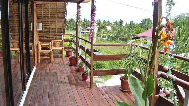 A wooden deck with wicker furniture and potted plants. - Hotel Sisters Inn  Moalboal (Moalboal)