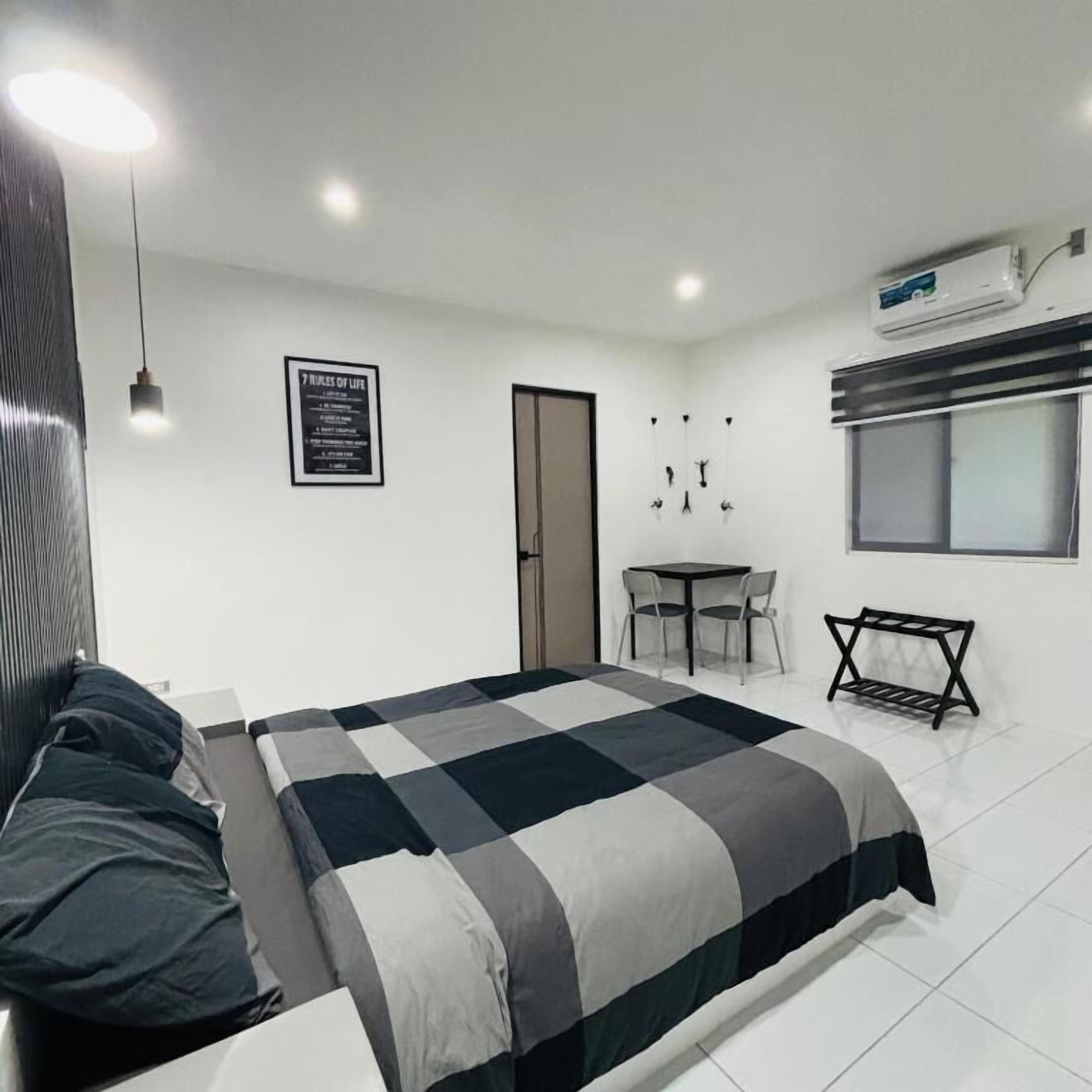 A modern bedroom with a bed, bedside table, and a small desk with chairs.