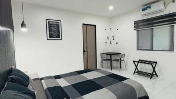 A modern bedroom with a bed, bedside table, and a small desk with chairs.