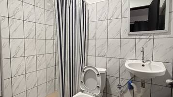 Un baño con inodoro, lavamanos y cortina de ducha.