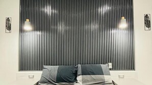 A modern bedroom with a checkered bedspread, a vertical panel headboard, and two bedside lamps. - Hotel Sisters Inn  Moalboal (Moalboal)