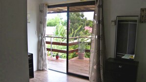 A room with a sliding glass door leading to a balcony with wooden flooring and potted plants. - Hotel Sisters Inn  Moalboal (Moalboal)