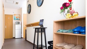 En gang med et træskrivebord, en computer og et skohold med slippers.